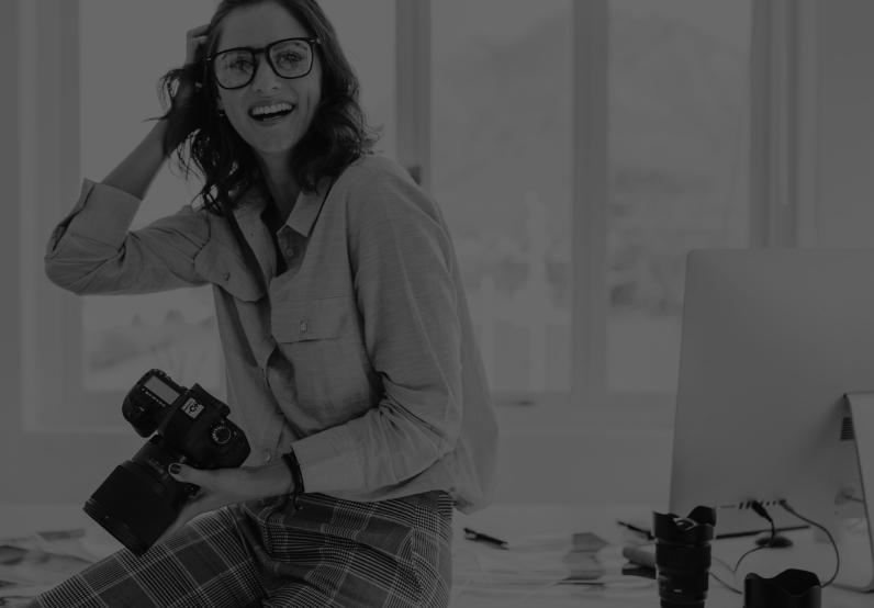 Image showing a female photographer holding a camera in front of a computer